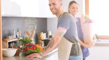 Bir çift evdeki mutfaklarında birlikte yemek pişiriyor.