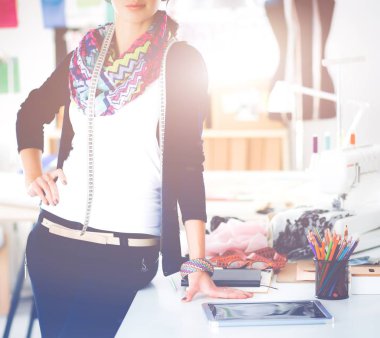 Güzel moda tasarımcısı stüdyoda duruyor.