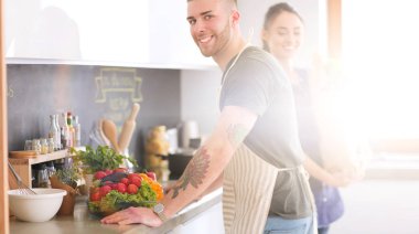 Bir çift evdeki mutfaklarında birlikte yemek pişiriyor.