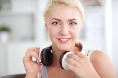 Evdeki genç ve güzel kadın kanepede oturup müzik dinliyor.