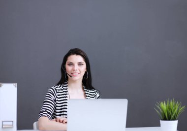 Masasında kulaklığı ve laptopuyla çalışan güzel bir iş kadını.