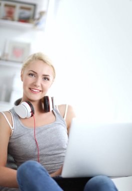 Evdeki genç ve güzel kadın kanepede oturup müzik dinliyor.