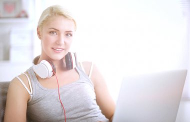 Evdeki genç ve güzel kadın kanepede oturup müzik dinliyor.
