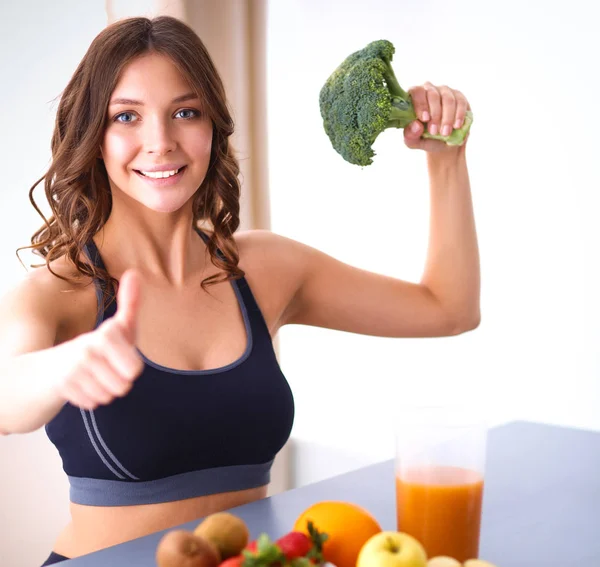 Girl sitting in kitchen on the desk with fruit and glasses juice — Stock Photo, Image