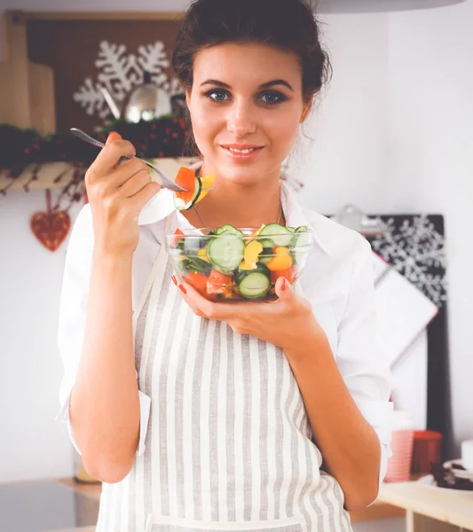 Jovem mulher comendo salada fresca na cozinha moderna — Fotografia de Stock