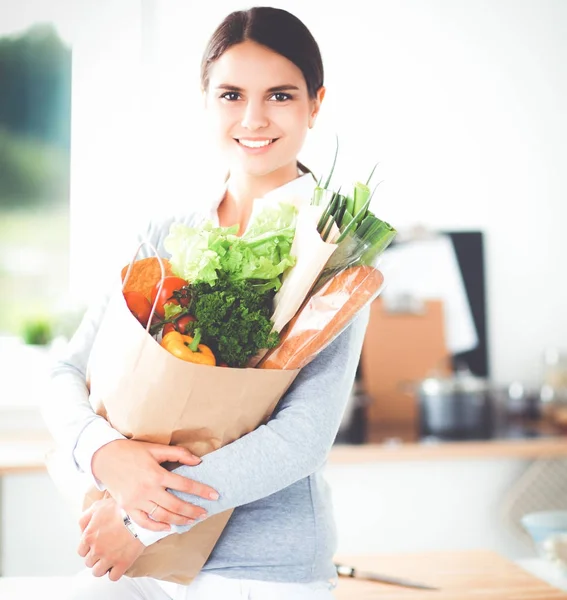 Young woman holding grocery shopping bag with vegetables . Standing in the kitchen — Stock Photo, Image