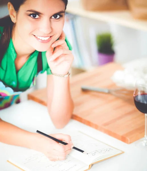 Glada vackra kvinna som står i hennes kök som skriver på en bärbar dator hemma — Stockfoto