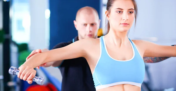 Hermosa mujer en el gimnasio haciendo ejercicio con su entrenador —  Fotos de Stock