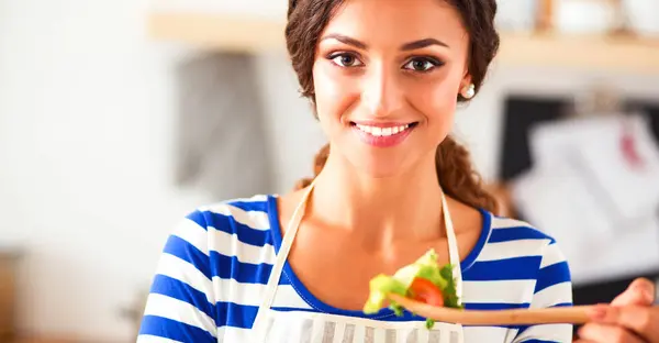 Giovane donna mangiare insalata fresca in cucina moderna — Foto Stock