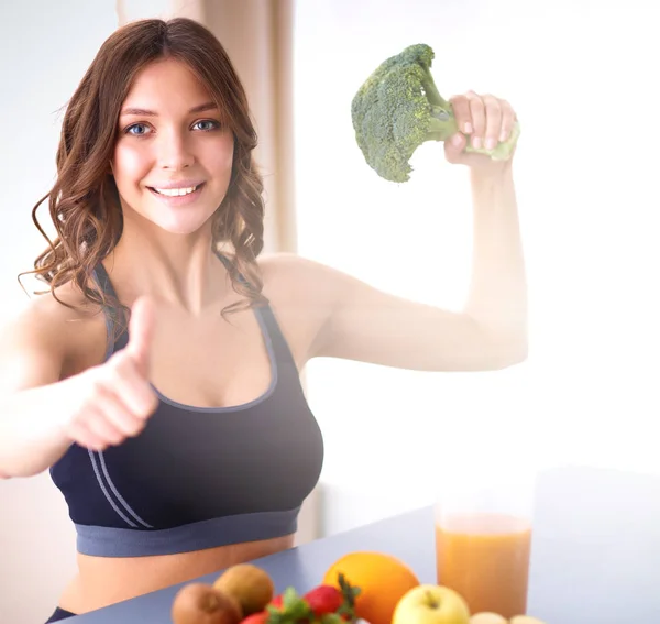 Menina sentada na cozinha na mesa com suco de frutas e copos — Fotografia de Stock