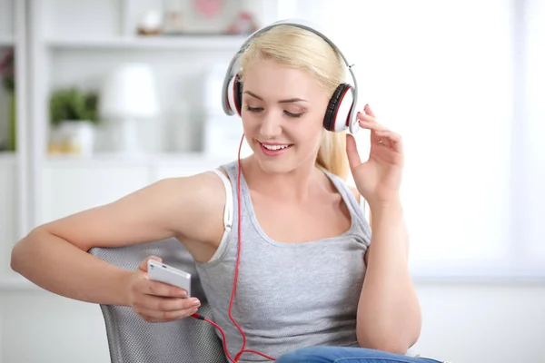 Jonge mooie vrouw thuis zitten op de bank en luisteren muziek — Stockfoto