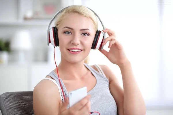 Jonge mooie vrouw thuis zitten op de bank en luisteren muziek — Stockfoto