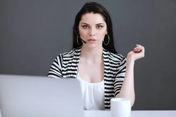 Schöne Geschäftsfrau am Schreibtisch mit Headset und Laptop — Stockfoto