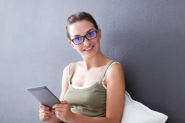 Attractive caucasian girl sitting on floor with cup and tablet near wall — Stock Photo, Image