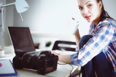 Dizüstü bilgisayar ile masaya oturan kadın fotoğrafçı. Kadın fotoğrafçı