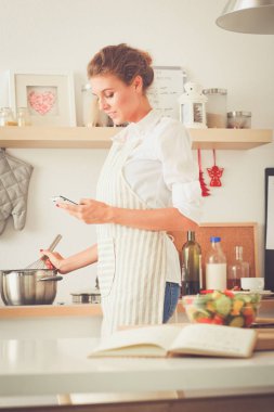 Gülümseyen kadın mutfakta bilgisayar ve kredi kartı kullanarak alışveriş online. Gülümseyen kadın
