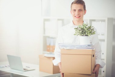 Gri arka plan üzerinde oturan gülümseyen genç adam portresi. Genç adam portresi