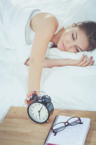 Una mujer joven apagando su despertador por la mañana. — Foto de Stock