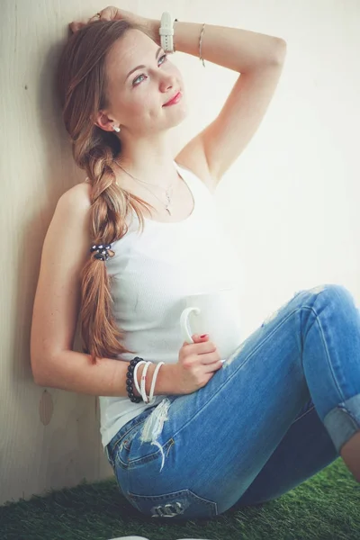 Hermosa mujer sentada en el suelo y sosteniendo una taza. Hermosa mujer —  Fotos de Stock