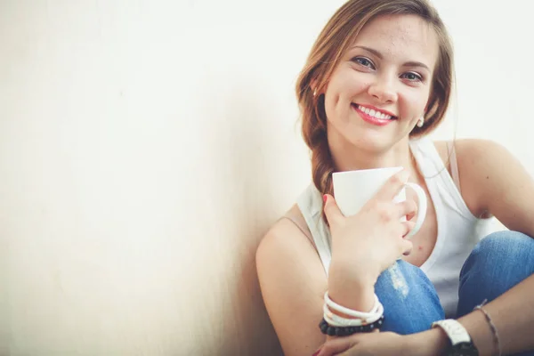 Hermosa mujer sentada en el suelo y sosteniendo una taza. Hermosa mujer —  Fotos de Stock