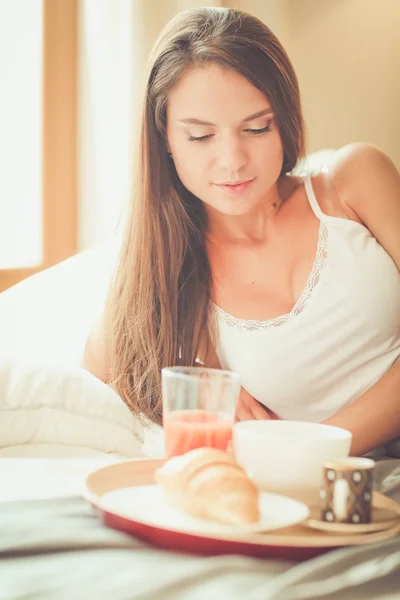 Mujer joven sentada en la cama con una taza de leche — Foto de Stock