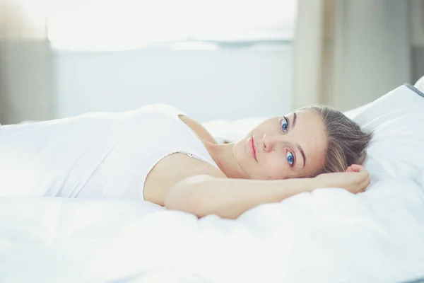 Piękna młoda kobieta leżąca wygodnie i błogo w łóżku. — Zdjęcie stockowe