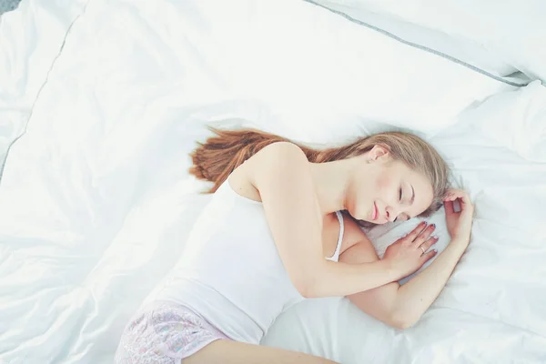 Una hermosa joven acostada en la cama cómoda y felizmente. — Foto de Stock