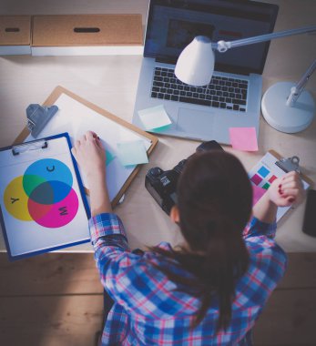Masada dizüstü bilgisayarla oturan kadın fotoğrafçı.