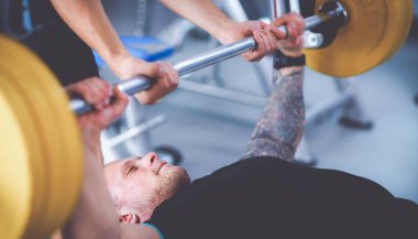 Genç adam eğitmen ile spor salonunda halter kaldırma