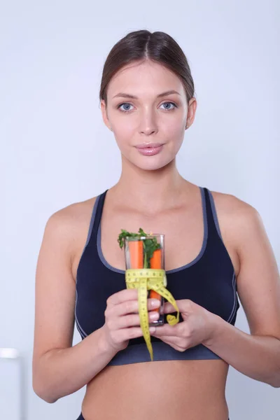 Mujer sosteniendo un vaso lleno de ensalada de frutas frescas con una cinta métrica alrededor del vaso. —  Fotos de Stock