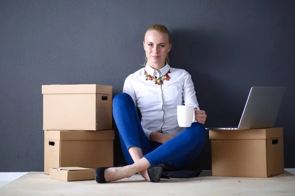 Woman sitting on the floor near a boxes with laptop . Businesswoman — Stock Photo, Image