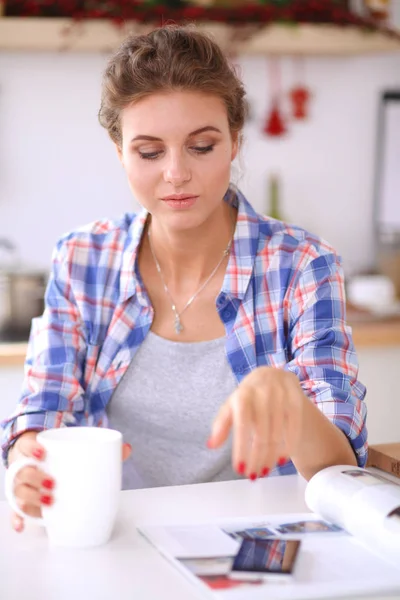 Mulher sorridente a segurar o telemóvel na cozinha. Mulher sorridente . — Fotografia de Stock