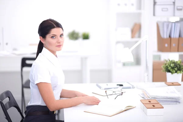 Atrakcyjna bizneswoman siedzi w biurze, odizolowana — Zdjęcie stockowe