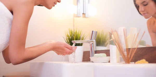 Jonge vrouw wassen haar gezicht met schoon water in badkamer — Stockfoto