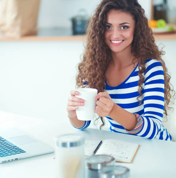 Lachende jonge vrouw met laptop in de keuken thuis — Stockfoto