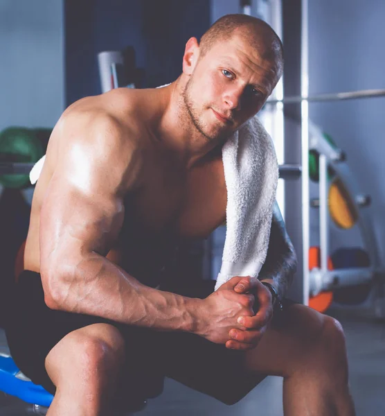 Joven hombre guapo se sienta después del entrenamiento en el gimnasio — Foto de Stock