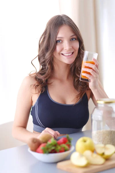 女孩坐在厨房的桌子上的水果和果汁的眼镜. — 图库照片