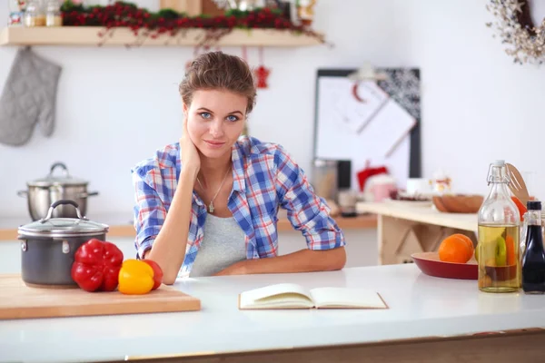 Mujer sonriente sosteniendo su teléfono celular en la cocina. Mujer sonriente . —  Fotos de Stock