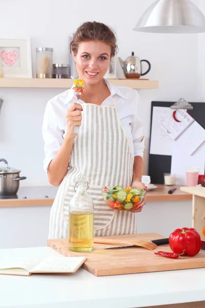 Wanita muda tersenyum menyiapkan salad di dapur . — Stok Foto