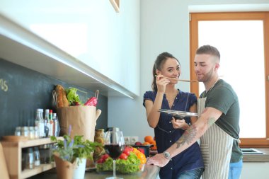 Bir çift evdeki mutfaklarında birlikte yemek pişiriyor.