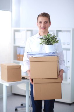 Gri arka plan üzerinde oturan gülümseyen genç adam portresi. Genç adam portresi