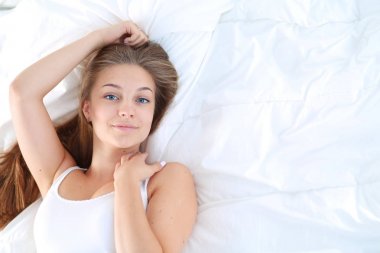 Yatakta rahat ve mutlu bir şekilde yatan güzel bir genç kadın..