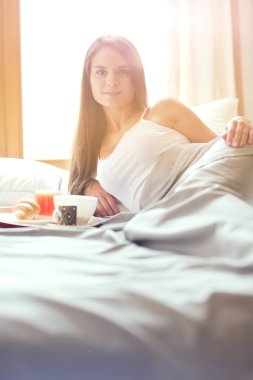 bir bardak süt ile yatakta oturan genç kadın