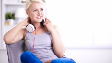 Evdeki genç ve güzel kadın kanepede oturup müzik dinliyor.