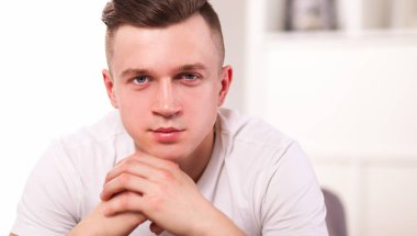 Genç adam sandalyede oturuyor.