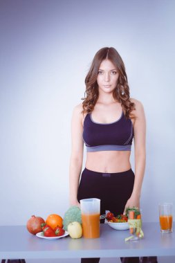 Sebzelerle masanın yanında duran genç ve güzel bir kadın..