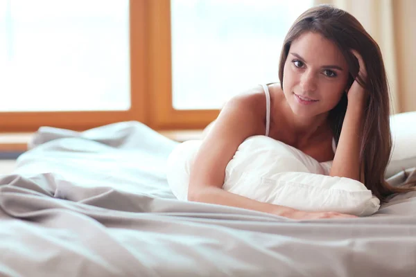 Hermosa morena acostada en la cama en casa — Foto de Stock