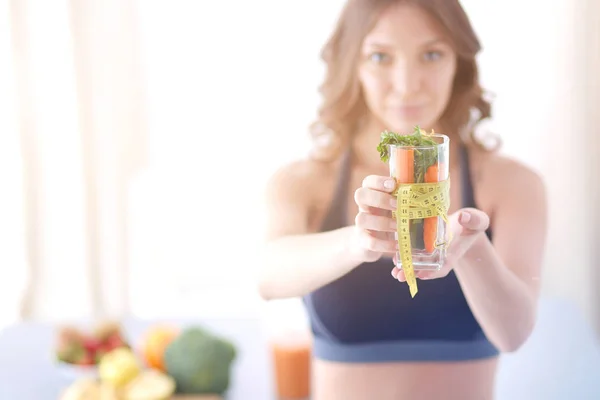 Mulher segurando um copo cheio de salada de frutas frescas com uma fita métrica ao redor do copo. — Fotografia de Stock