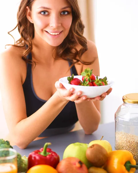 Дівчина сидить на кухні на столі з фруктами і келихами з соком — стокове фото