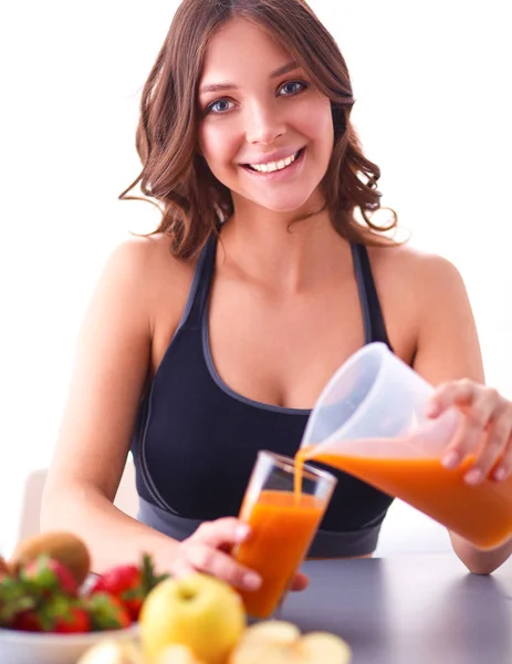 Fille assise dans la cuisine sur le bureau avec des fruits et des verres avec du jus — Photo